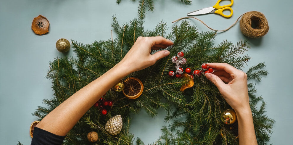 woman making handmade christmas wreath. top view.